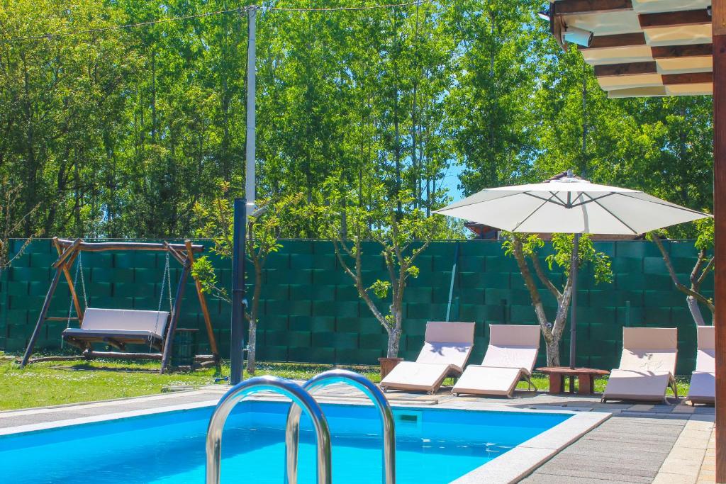 an umbrella and chairs next to a swimming pool at Vikendica Drinski LAD in Loznica
