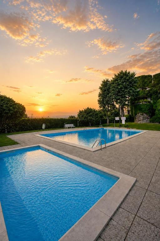 a swimming pool with a sunset in the background at Aloha Pool Apartment - Free Parking - Sirmione in Desenzano del Garda