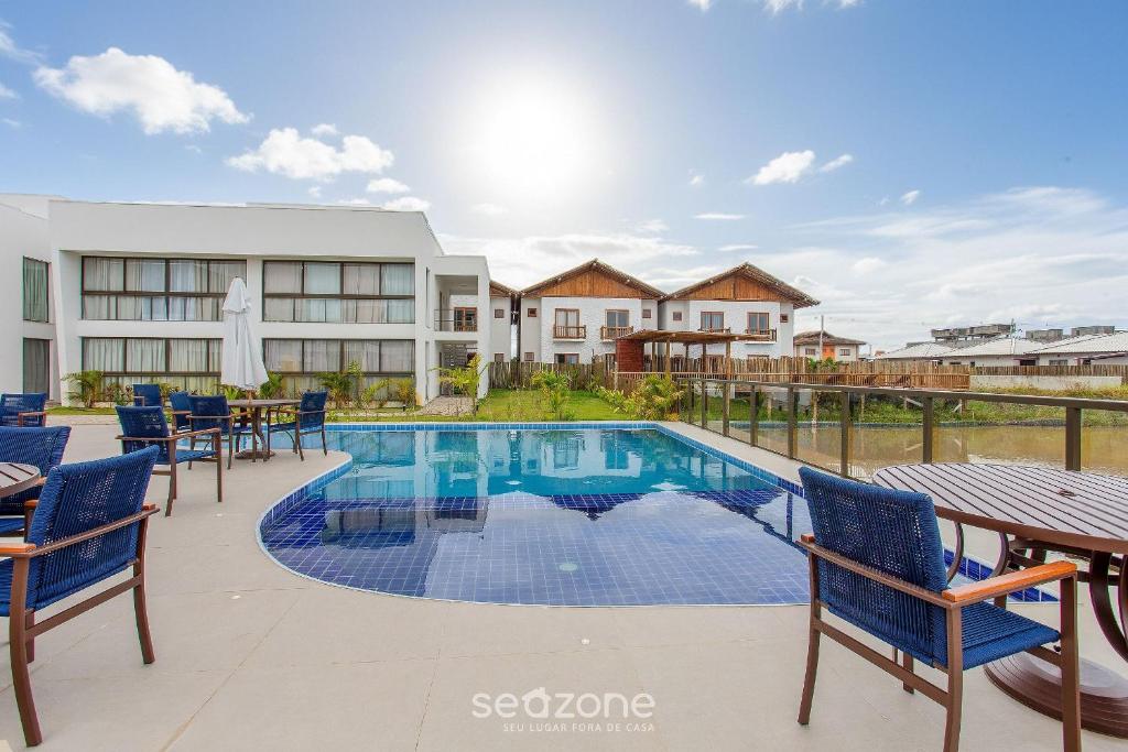 a swimming pool with chairs and tables in front of a building at Modern and sophisticated apartments near the beach in Maraú – VLL in Marau