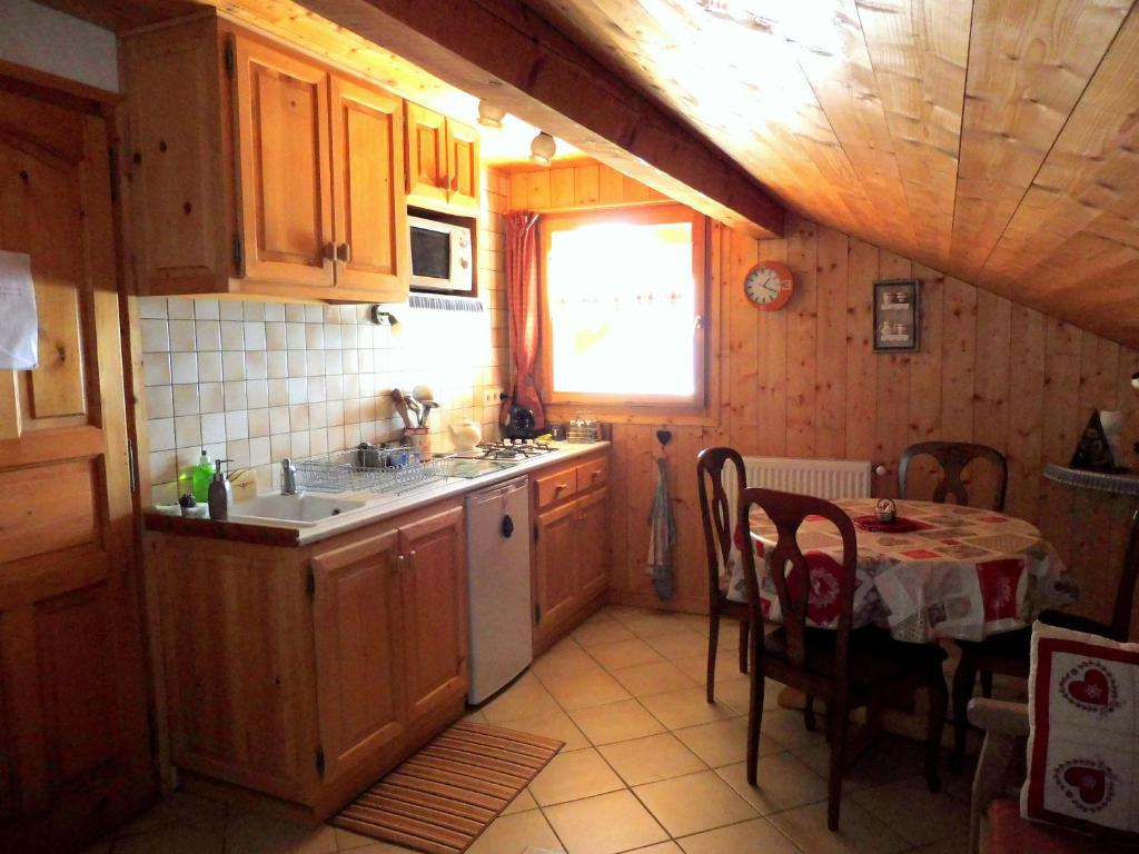 a kitchen with wooden cabinets and a table with a tablecloth at Chambres d'hôtes les Terrasses de Varme in Sallanches