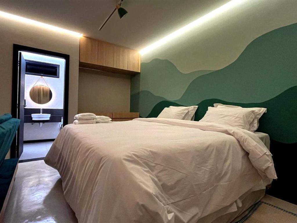 a bedroom with a white bed with a green wall at Apart-hotel Theotókos Flats in Piauí