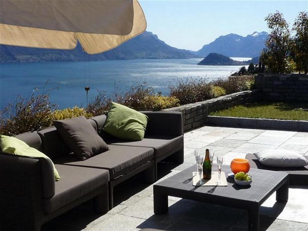 a patio with a couch and a table with a view of the water at Villa Panoramica in Menaggio