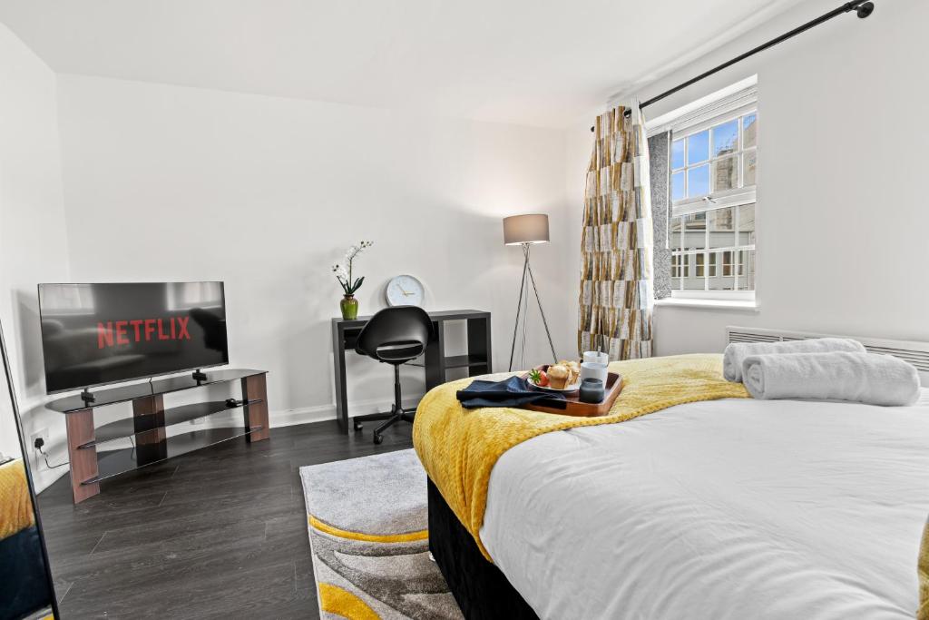a bedroom with a bed and a tv and a desk at Cheshire Gold- studio apartment, Warrington in Warrington