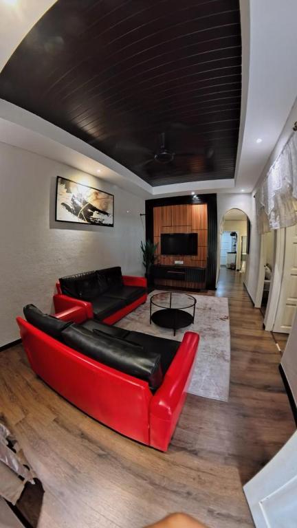 a living room with two red couches and a television at BELLA COTTAGE in Pantai Cenang