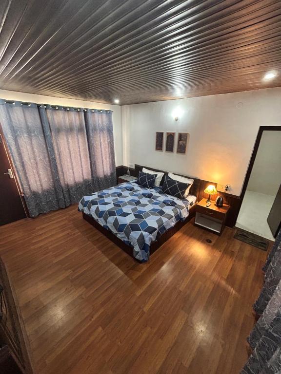 a bedroom with a bed and a wooden floor at Hotel Devidyar in Manāli