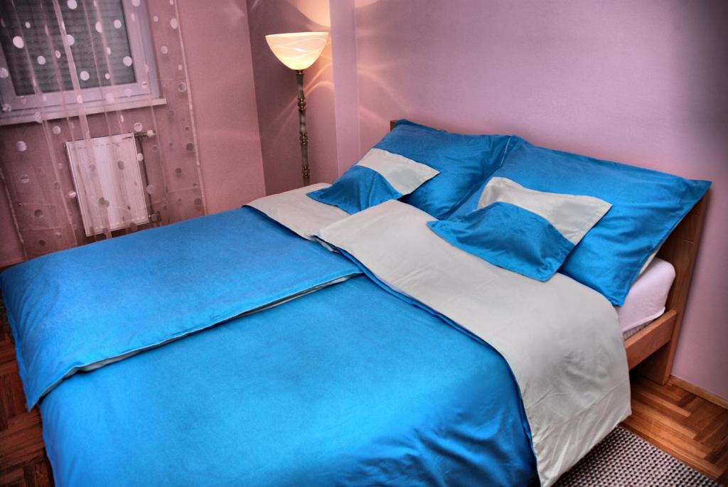 un letto blu e bianco in una camera da letto viola di Apartman Milkovic 2 a Sombor