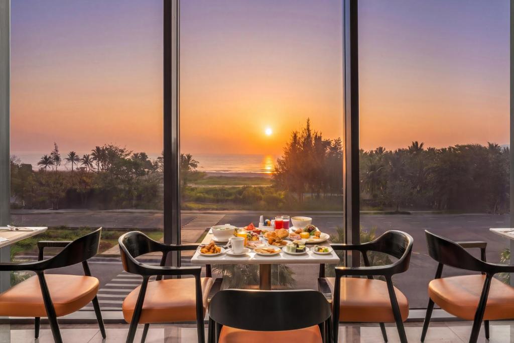 Breakfast is served beside floor-to-ceiling windows overlooking the sea at sunset.