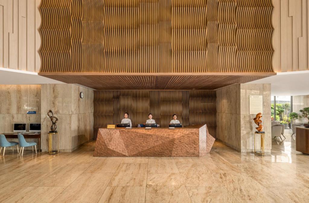 A formal reception desk beneath a sculptural wood ceiling feature.