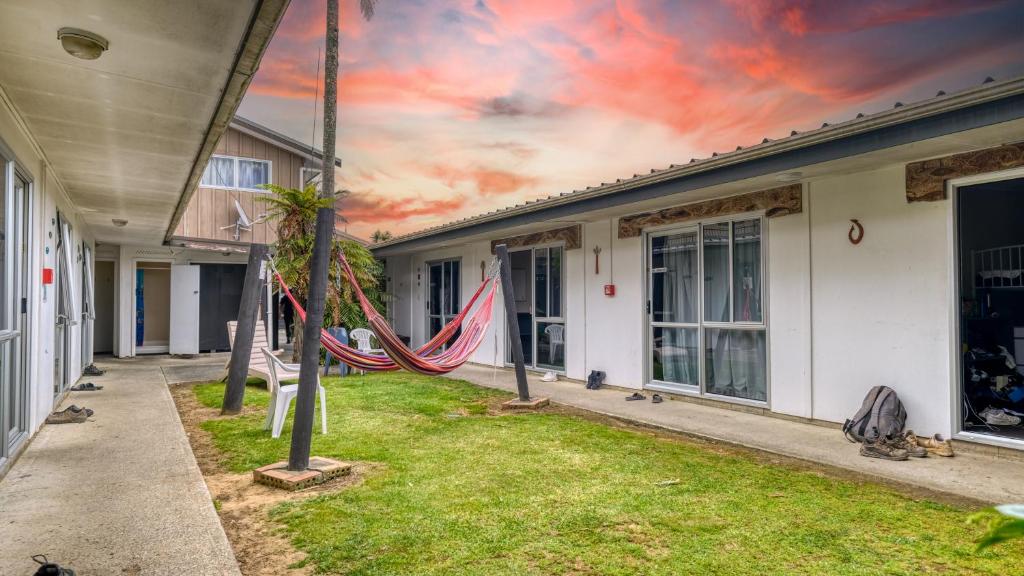 a hammock in a yard between two buildings at Beachcomber Lodge & Backpacker in Kaitaia
