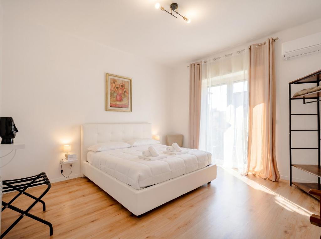 a white bedroom with a white bed and a window at Bari Home in Bari