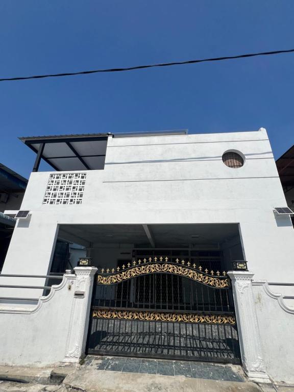 a white building with a gate and a blue sky at wawa homestay in Butterworth