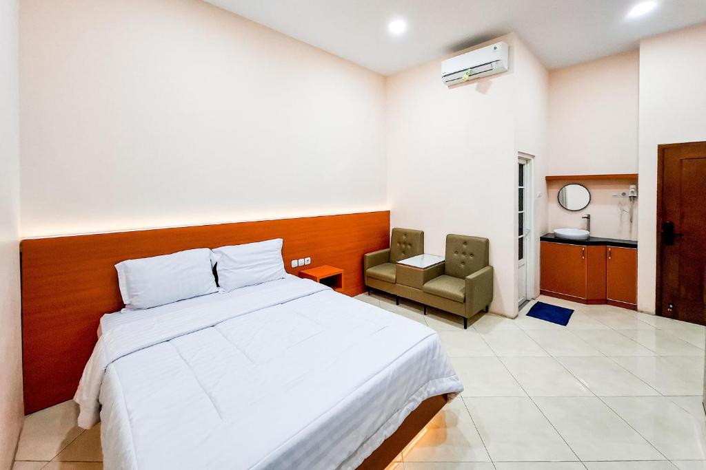 a bedroom with a bed and a chair in it at Abbas Syariah Hotel near Menara Kudus Mitra RedDoorz in Kudus