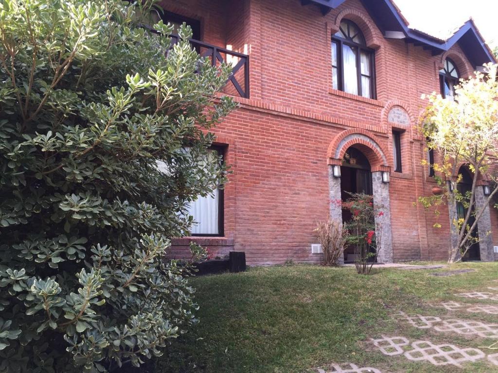 a red brick house with a tree in the yard at DUPLEX Casa 100 m2 CARILO HOUSE Complejo Residencial Sin Serv in Carilo