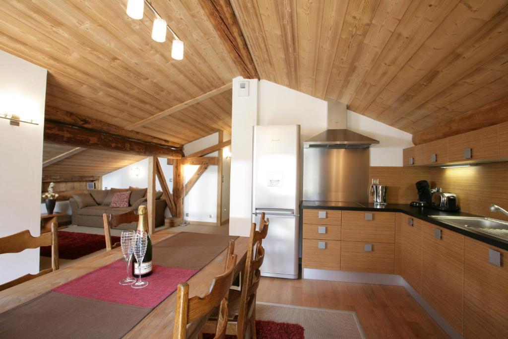 Il comprend une cuisine dotée de plafonds en bois et d'une table avec des chaises. dans l'établissement La Grange De L'Aiguille, à Chamonix-Mont-Blanc