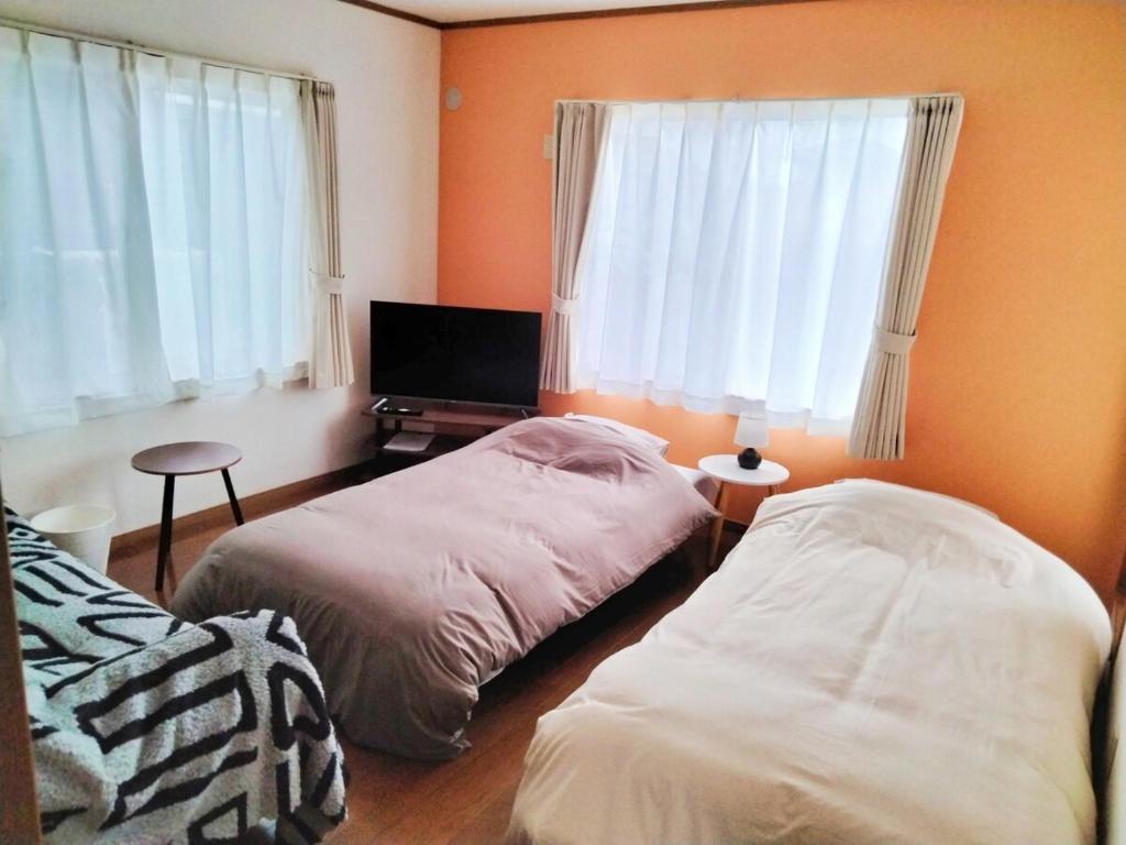 a bedroom with two beds and a flat screen tv at Winston in Chiba
