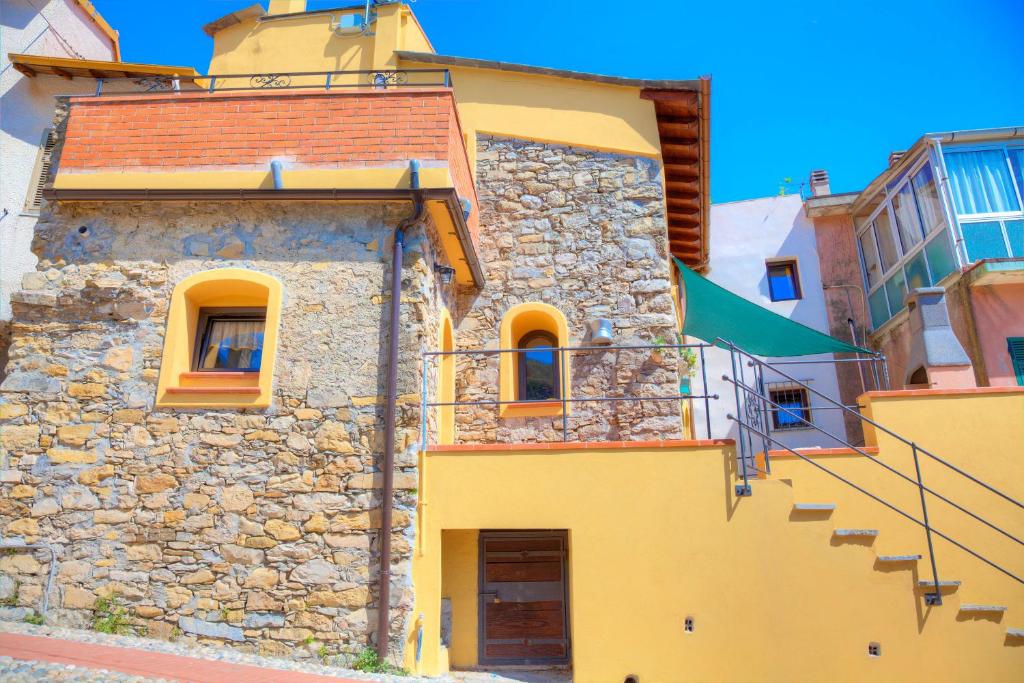 un edificio amarillo con escaleras y una bandera en La Casa di Pietra, en Villa Faraldi