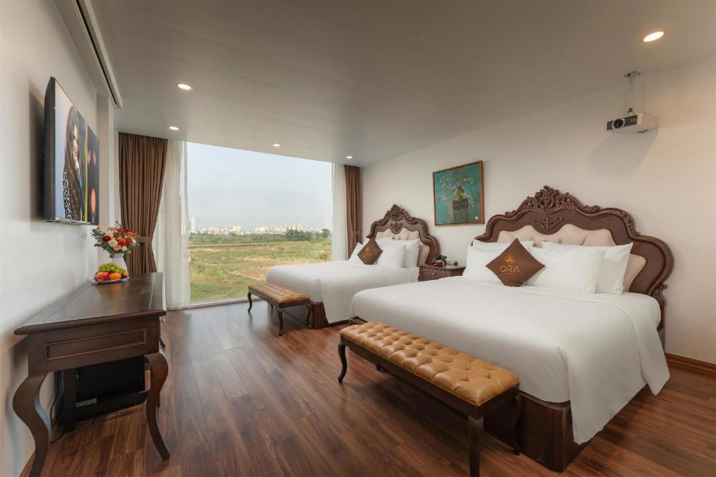 a bedroom with two beds and a desk and a window at ORA Hotel in Văn La
