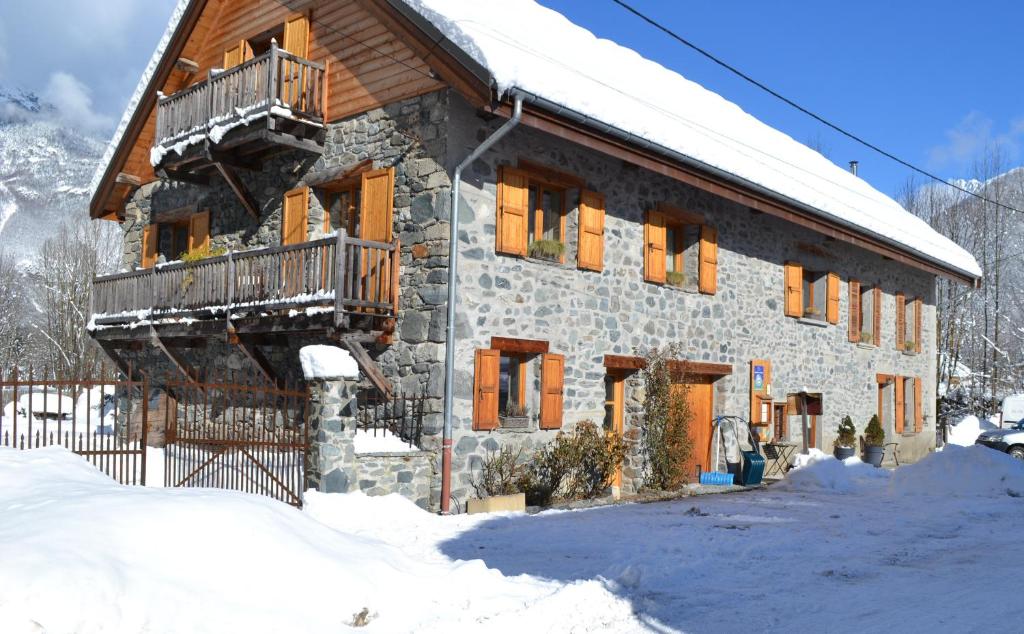 un edificio de piedra con balcón en la nieve en La Clé des Bois en Le Bourg-dʼOisans