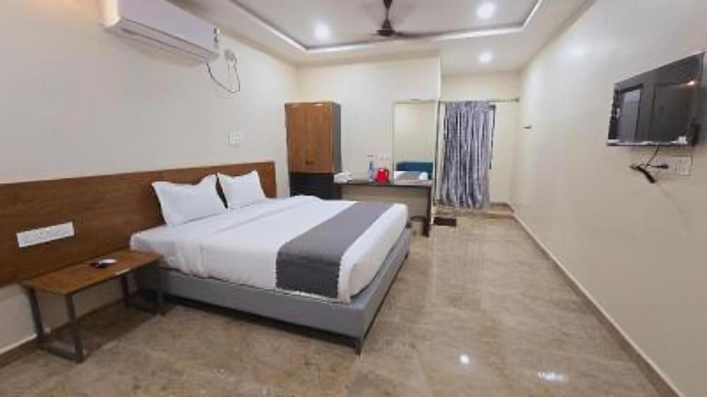 a hotel room with a bed and a television at Hotel VAAMANA STAYS in Tirupati