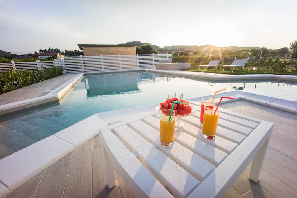 dos bebidas en un banco blanco junto a una piscina en Hotel Palmensis, en Marina Palmense