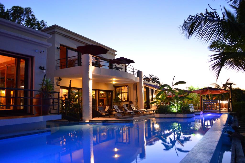 une grande maison avec une piscine en face de celle-ci dans l'établissement Le Gite du Bonheur Guest House & Car Rental, à Tamarin