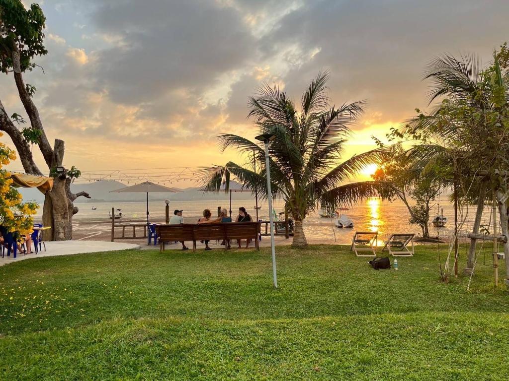 a group of people sitting on a bench near the beach at Rimlay Bay View in Ko Yao Noi