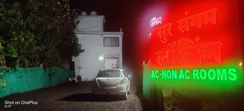 a car parked in front of a building with a neon sign at Hotel Sur Sangam in Nashik
