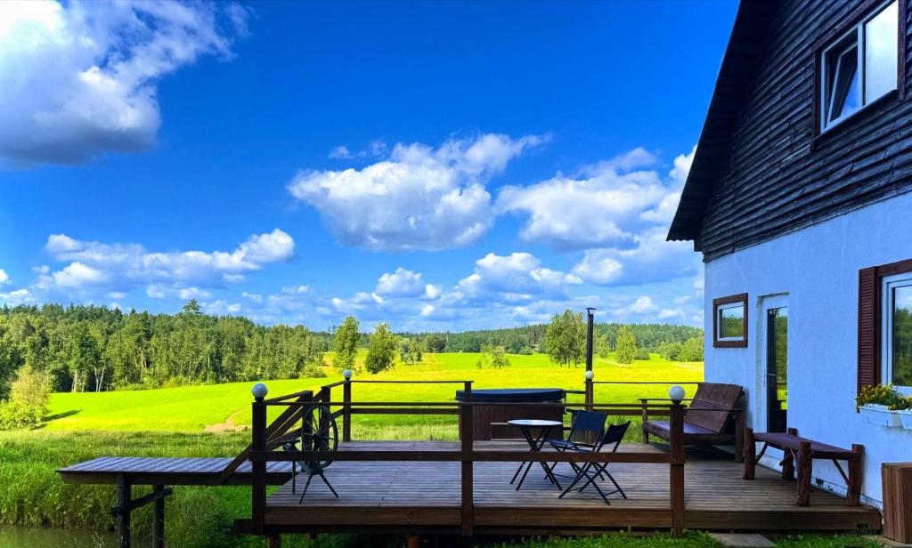 a wooden deck with chairs and a table next to a house at Forest Lodge & Spa in Gauja National Park - Kaķukalns in Straupe