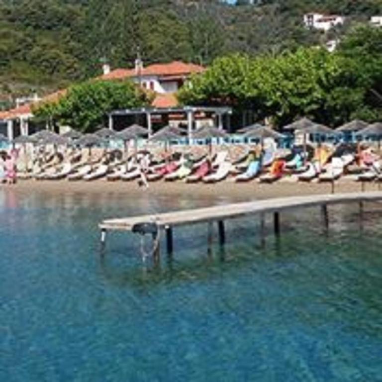 a group of chairs sitting on a beach in the water at Maniatis Garden in Achladies