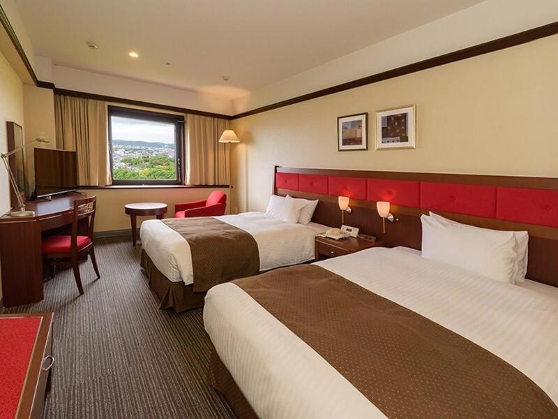a hotel room with two beds and a desk at Okayama International Hotel in Okayama