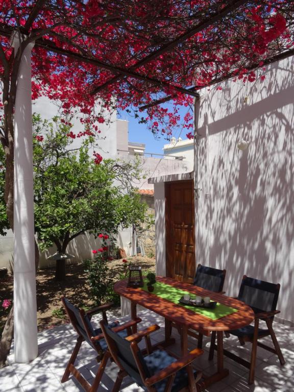 a table and chairs under a pergola with red flowers at Neoclassical House in Chania