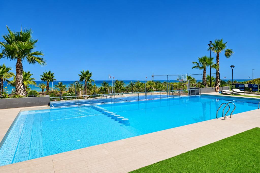 a large swimming pool with palm trees in the background at Beachfront Luxury Apartments by NRAS in Arenales del Sol
