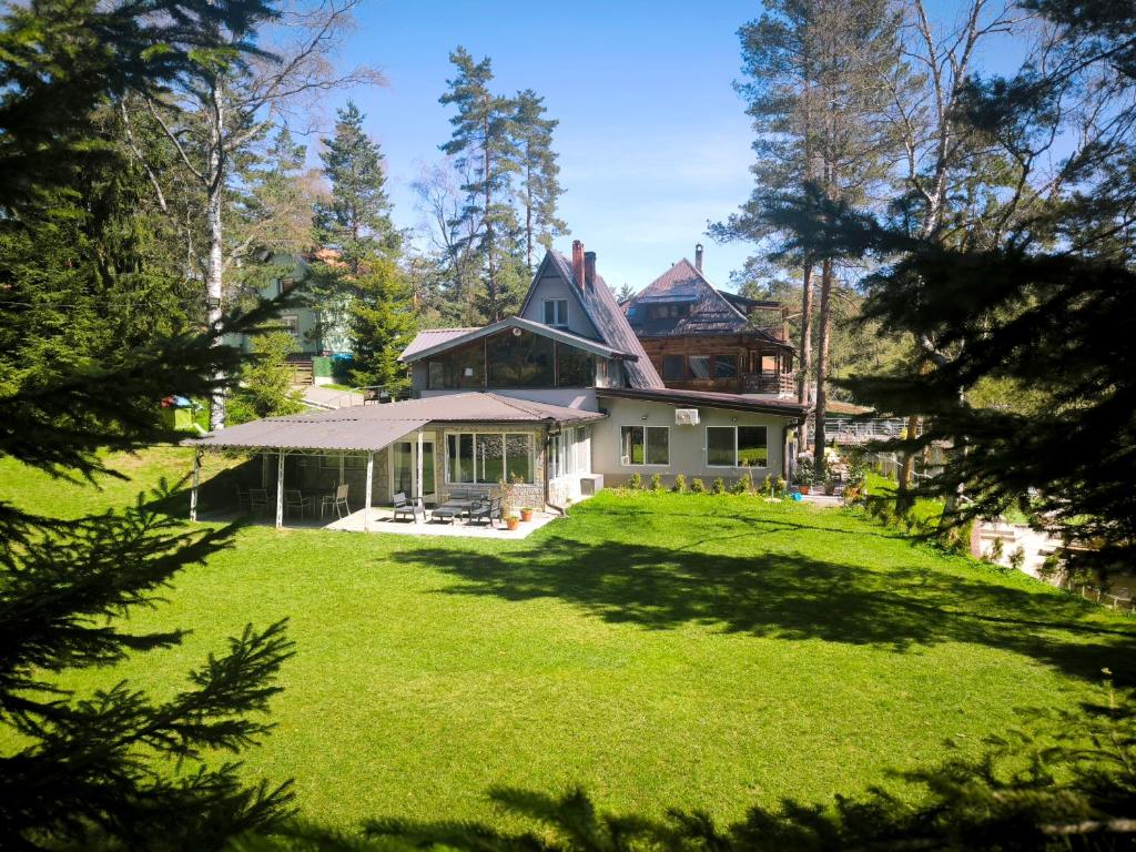 a house on a grassy hill with trees at Vila POGLED Wellness i spa in Divčibare