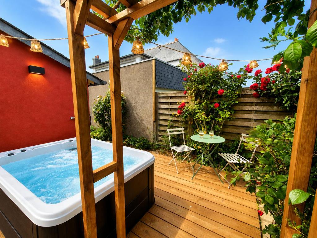 an outdoor hot tub on a deck with a garden at Chez Simone in Ploemeur
