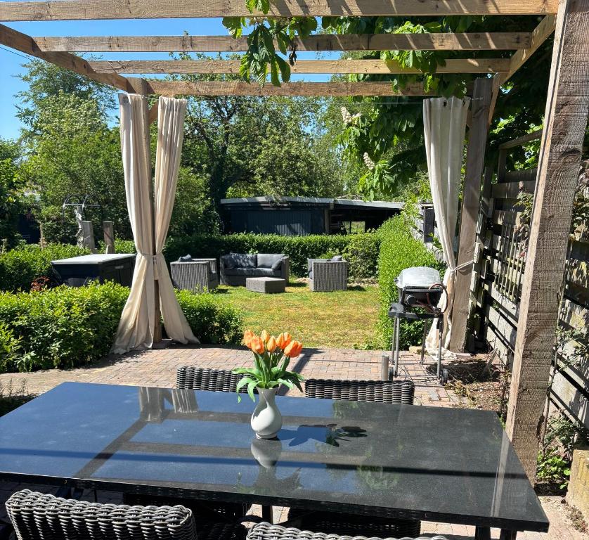 a table with a vase of flowers on a patio at De Drentse Rust - Het Atelier in Emmer-Compascuum