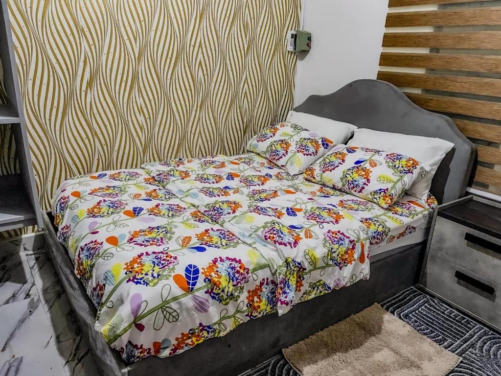 a bed with a floral comforter and pillows at Wiwi Appartement in Kinshasa