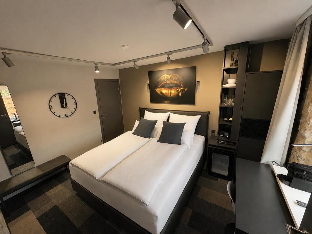 a bedroom with a large bed and a clock on the wall at NOX HOTEL - Digital-Check-In - No Reception - nahe Bretten & Karlsruhe - 1 Grey in Wössingen