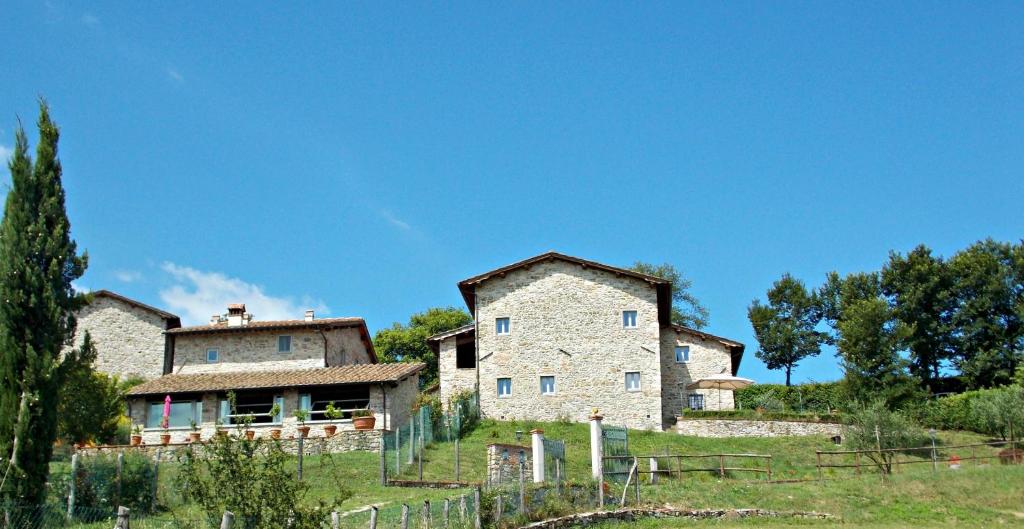 an old stone house in a field with a fence at Casale Mocali in Fattoria del Mulinaccio