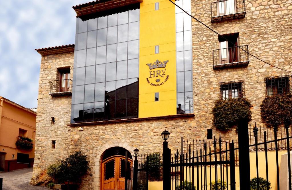 um edifício amarelo com um relógio na lateral em Hotel Restaurante Verdia em Sueras