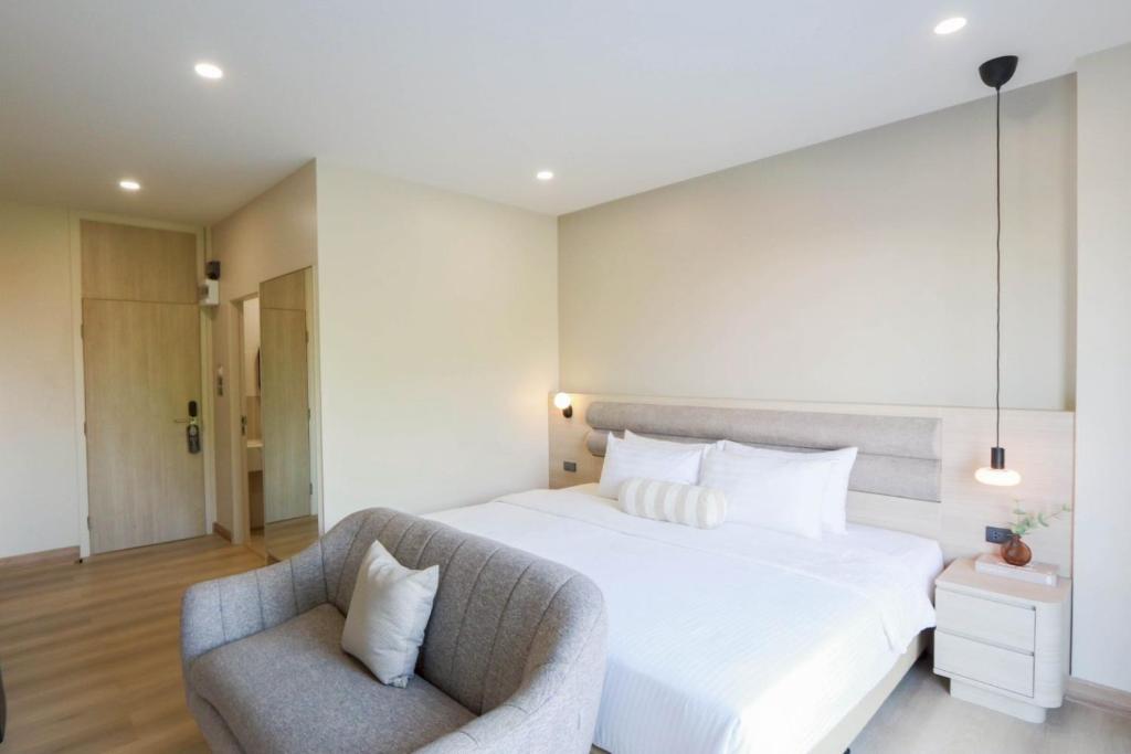 a bedroom with a large white bed and a chair at Aster Canopy Suites & Living in Rayong