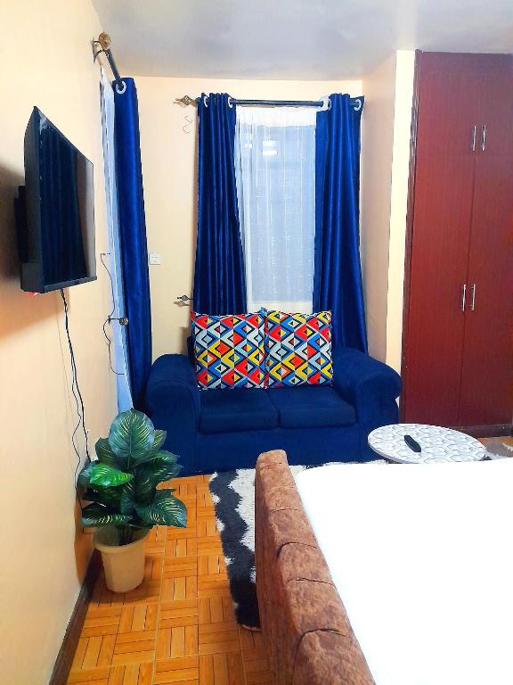 a living room with a blue couch and a television at Sifa Stays in Ongata Rongai 