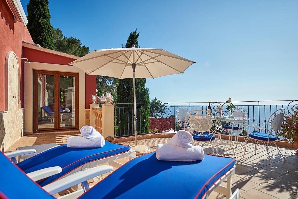 a patio with two blue chairs and an umbrella at Las Escaleras - Villa PEKA - 4S in Port d’Andratx