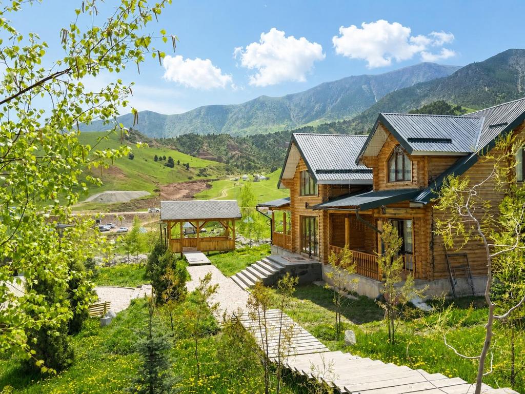 an image of a log house with mountains in the background at Мурас Эко - Ресорт in Alamedin