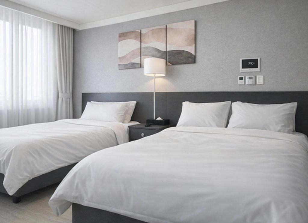 two beds in a hotel room with white sheets at 썸원호텔 in Yŏsu
