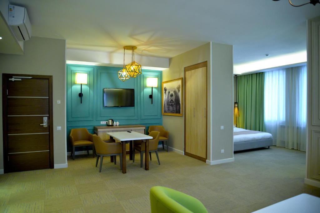 a hotel room with a bed and a table and chairs at GREEN Which Hotel Kokshetau in Kokshetau