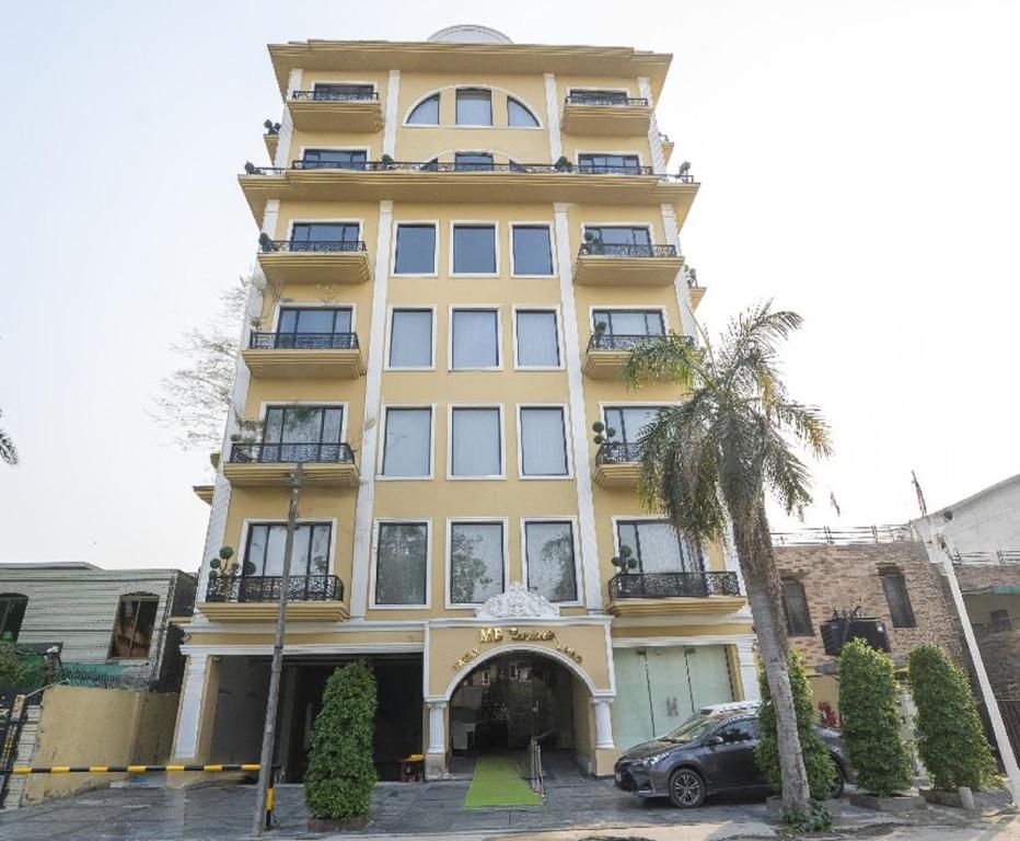 a yellow building with a car parked in front of it at La Maison Royale Hotel in Lahore