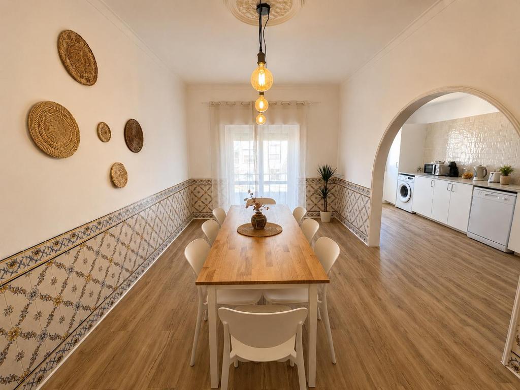 a dining room with a table and white chairs at Charneca Mar & Sol in Charneca