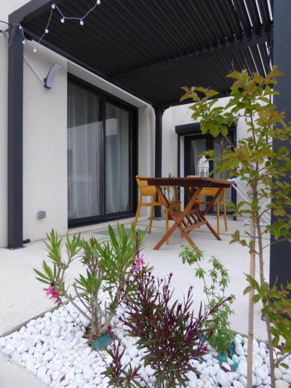 a patio with a wooden table and some plants at studio des olivières in Montpeyroux