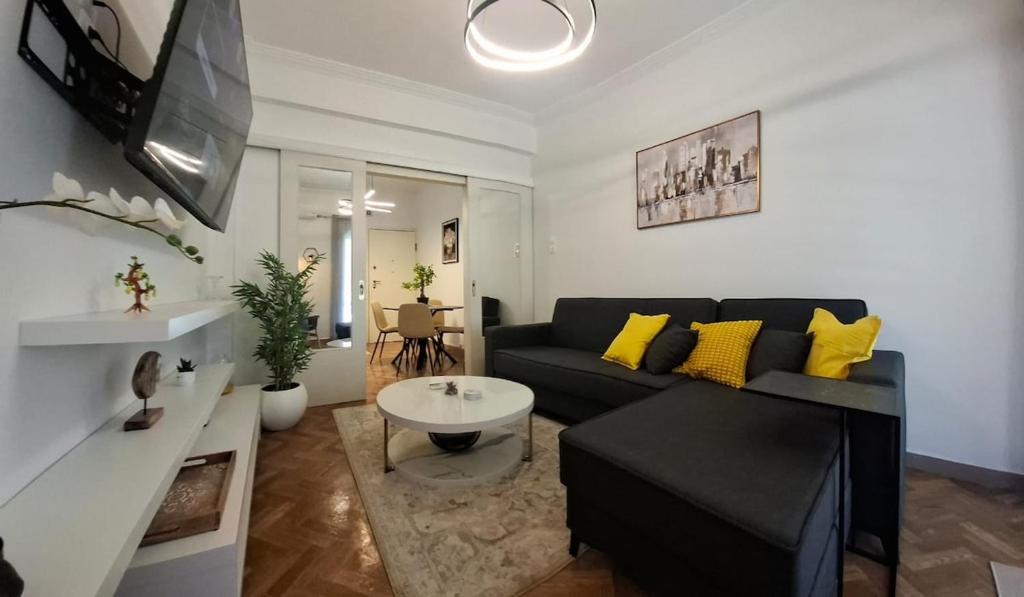 a living room with a black couch and yellow pillows at Lemon House in Athens