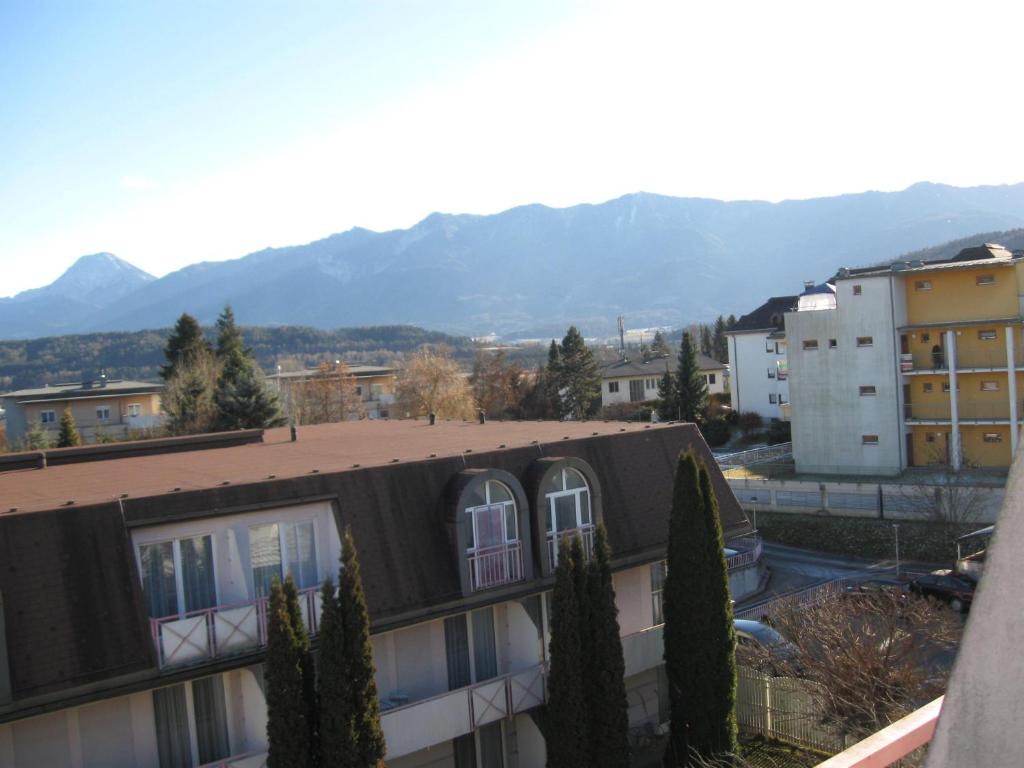 a building with a roof with mountains in the background at Holiday Apartments Warmbad in Villach